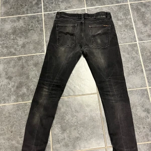 Svarta Nudie Jeans slim straight 31/30 - Snygga svarta jeans från Nudie Jeans . Klassisk femficksmodell med dragkedja och Nudie-logga på bakfickan. Jeansen har en mörk tvätt med ljusare partier och är tillverkade i stretchig bomull för skön passform. Stretch passar 32/32 bättre 