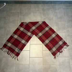  halsduk från Burberry - Snygg halsduk från Burberry,Gjord av 100% lammull. Mycket fint skick, längden är 130cm (ej fransar inräknat) hör av er vid frågor eller funderingar!✌️👌🤩