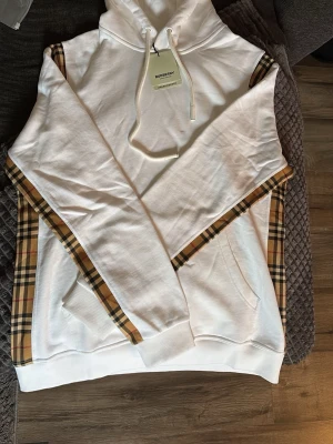 Burbbery hoodie vit - En jätte fin och skönt Burbbery hoodie som tyvärr inte passar, aldrig andvänd och jätte skön och fin vit hoddie, passar L med 