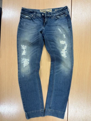 Blå distressed jeans från Jacob Cohen - Snygga blå jeans från Jacob Cohen med slitna detaljer och ljus tvätt. Klassisk femficksmodell med broderad logga på bakfickan och patch i grått. Jeansen har rak passform och är tillverkade i mjukt denimtyg med coola slitningar framtill.