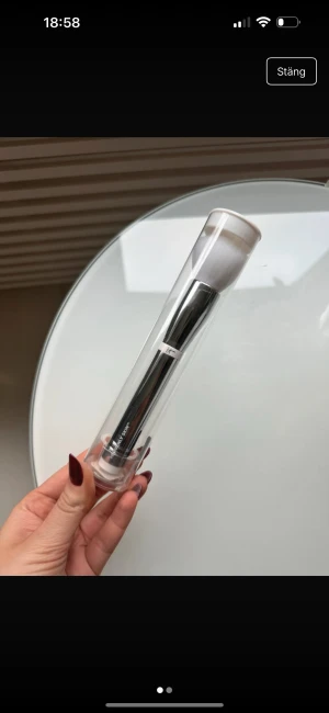 IT Cosmetics - Sminkborste från IT Cosmetics med silvrigt handtag och täta vita syntetiska borst. Perfekt för applicering av foundation eller puder och har en stilren design.