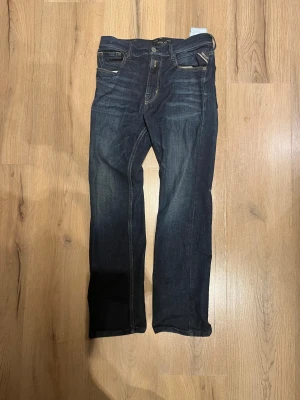 Replay mörkblå jeans straight fit - Snygga mörkblå jeans från Replay med klassisk femficksdesign och raka ben. Jeansen har kontrastsömmar, läderpatch med Replay-logga bak och är tillverkade i slitstarkt denim. Perfekta för dig som gillar en tidlös och clean look.