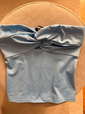 Ljusblå bandeau tubtopp från Bikbok - Säljer en ljusblå bandeau tubtopp från Bikbok i storlek XS. Toppen har en snygg twistad detalj framtill och kommer inte längre till användning🩵