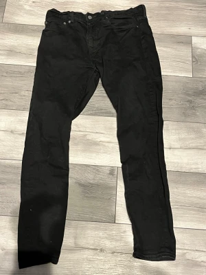 Svarta Levi's jeans - Svarta Levi's jeans med klassisk femficksdesign och smal passform. Jeansen har en diskret Levi's-logga på bakfickan. Storleken är W34 och L32. Inga hål eller fläckar på jeansen. Perfekt för dig som gillar en clean och stilren look. Pris kan diskuteras vid snabb affär.