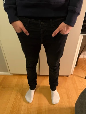 Svarta slim fit jeans Reserved & Co - Svarta slim fit jeans från Reserved & Co med klassisk femficksdesign och bälteshällor. Jeansen har en smal passform och är tillverkade i ett stretchigt material som sitter snyggt längs benen. Perfekta för dig som gillar en stilren och enkel look.