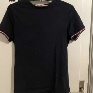 Marinblå t-shirt från Moncler - Snygg marinblå t-shirt från Moncler med korta ärmar och diskret logga på ärmen. Perfekt för en stilren look. Hör av er vid minsta fundering🤔Nypris 2100kr