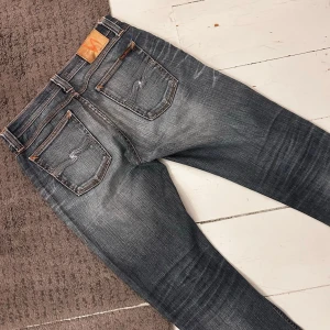 Mörkblåa/Mörkgråa Nudie Grim Tim Jeans - Riktigt snygga Nudie Jeans i Grim Tim | W29 L32 | Nypris 1699kr | Riktigt fint skick, knappast några tecken på användning, förutom att modell-lappen slitits ner, därav ser man inte exakta modell (gissar på Grim Tim). | Midja: 39-42cm (Stretch) längd: 104cm | Tydliga fades, tydliga honeycombs & whiskers. | Skriv vid minsta fundering, pris ej hugget i sten! 