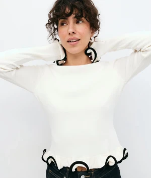 Vit långärmad topp med svarta volangdetaljer - Supersöt vit långärmad topp från Gina Tricot med  svarta volangdetaljer längs nederkant och ärmslut. Helt ny med lappen kvar💕 slutsåld på hemsidan 