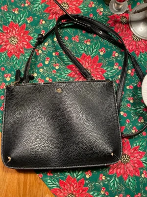 Svart axelväska från Lauren Ralph Lauren - Snygg svart axelväska i skinn från Lauren Ralph Lauren med två separata fack och guldfärgade dragkedjor. Väskan har justerbar axelrem och diskret RL-logga i metall framtill. Perfekt storlek för det viktigaste och stilren design.