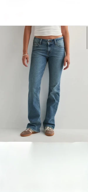 Superlow bootcut Levis jeans - Säljer ett par klassiska Levi's 505 jeans i blå tvätt med bootcut-snitt. Jeansen har normal passform, fem fickor och den ikoniska Levi's-lappen bak i midjan. Materialet är slitstarkt denim i bomull och modellen har en midwaist. Perfekt för dig som gillar retrovibe och tidlös stil.
