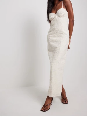 Vit långklänning med tunna axelband - Supersnygg vit långklänning med tunna axelband och figurnära passform. Klänningen har en strukturerad yta och en slits bak för extra rörelsefrihet. Perfekt för dig som vill sticka ut med en elegant och modern look. Aldrig använt 