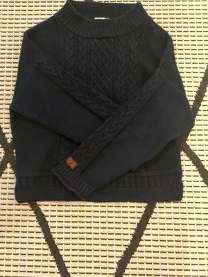 Mörkblå stickad tröja Boomerang S - Snygg mörkblå stickad tröja från Boomerang i storlek S. Tröjan har ett klassiskt flätmönster framtill och på ärmarna, samt ribbade muddar vid hals, ärmslut och nederkant. Perfekt att matcha outfits!💙