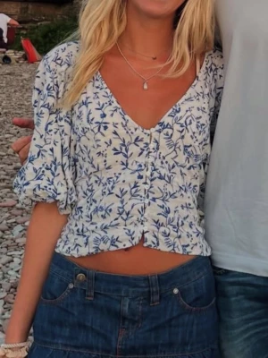 Blommig vit och blå blus med puffärm - Skit snygg blommig topp🙏🏼knappen längst ner har gått sönder, men tror inte det gör jättemycket och det går ju såklart att sätta dit en ny💕💕