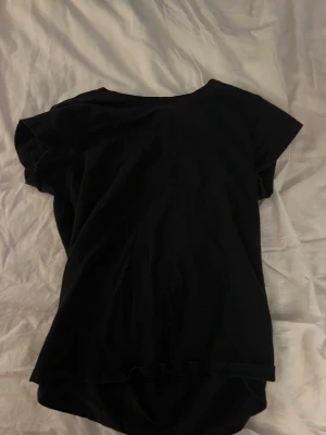 Svart basic t-shirt i bomull - En enkel svart t-shirt med rund hals och korta ärmar. Tillverkad i mjuk bomull som känns skön mot huden. Perfekt för dig som gillar en clean och stilren look. Passformen är normal och t-shirten är lätt att matcha med allt.