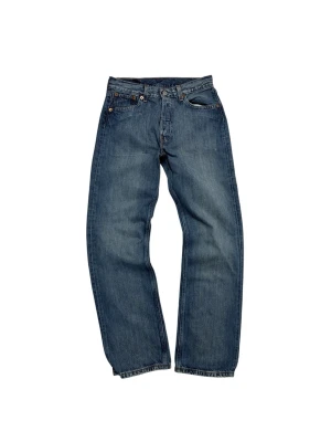 Levi's 501 blå jeans W29 L30 - Klassiska Levi's 501 jeans i blå tvätt med raka ben och normal passform. Jeansen har fem fickor, knappgylf och ikonisk läderpatch bak i midjan. Tillverkade i slitstarkt bomullsmaterial med snygga kontrastsömmar och röd Levi's-tag på bakfickan.
