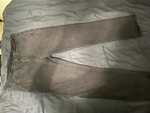 Svarta chinos från Hampton Republic - Svarta chinos från Hampton Republic med regular fit och comfort stretch. Snygga detaljer som röd söm på insidan av midjan och klassiska fickor med knapp bak. Perfekta för dig som vill ha en stilren och bekväm look.
