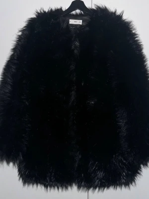 Svart pälsjacka från MNG - Säljer en svart fluffig pälsjacka från MNG i storlek S. Jackan har en oversized look med långärmade ärmar och är tillverkad i syntetiskt pälsmaterial. Perfekt för dig som vill ha en statement piece med mycket attityd.