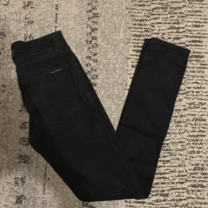 Svarta skinny jeans från Nudie Jeans - Svarta jeans från Nudie Jeans med skinny passform och klassisk femficksdesign. Byxorna har svarta sömmar, svart läderpatch och subtil Nudie Jeans-logga på bakfickan. Tillverkade i stretchig bomull för en tajt och bekväm känsla. Nyshick och jätte snygga och moderna jeans. Priset kan diskuteras 👍