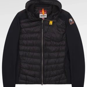 Svart Parajumper cardigan jacka - Säljer en svart cardigan jacka från Parajumper med huva och dragkedja framtill. Jackan har quiltad framsida och rygg i glansigt material, samt ärmar i stickad struktur. Märkets patch sitter på ena ärmen och det finns en gul detalj vid halsen. Finns storlek M också.Den är äkta