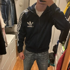 Mörkblå vintage adidas zip - Stilren retro adidas zip som jag knappt använder. Storlek Large men skulle säga att den passar mer Medium. Priset är ej hugget i sten! Jag på bilden är 179 cm lång