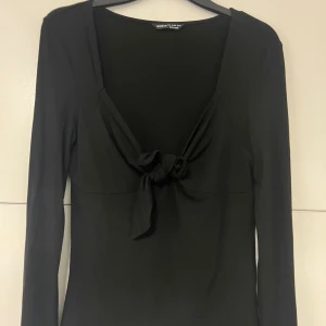  Långärmad topp med knyt  - Svart långärmad topp med snygg knytning framtill och djup v-ringning.