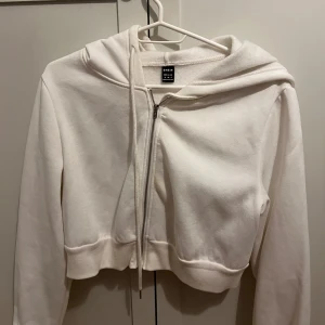 Vita och svarta hoodies från SHEIN - Två stilrena hoodies från SHEIN, en i vitt och en i svart. Båda har dragkedja framtill, huva med snörning och är croppade i modellen. Perfekta för en chill och avslappnad look.