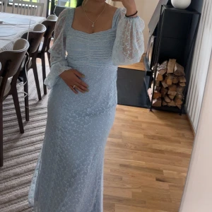 Bubbleroom occasion  - Säljer en ljusblå långklänning med transparenta, puffiga långärmar och vackert spetsmönster som jag bara använt en gång! Klänningen har en fyrkantig urringning och figurnära passform. Perfekt för dig som vill ha en romantisk och feminin look.  Passar som gästklänning till bröllop eller födelsedagsfest 