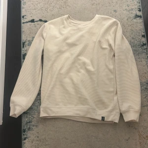 Beige ribbad tröja från Kappahl - Säljer en stilren beige ribbad tröja från Kappahl. Tröjan har rund halsringning, långa ärmar och breda muddar vid ärmslut och nederkant. Perfekt för dig som gillar en enkel och clean look.