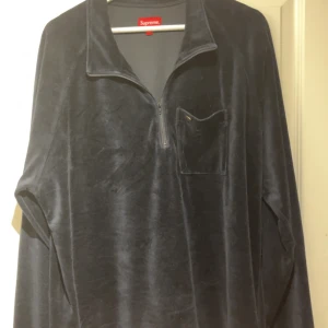 navy Supreme half zip tröja XL - Supreme svart långärmad tröja i mjuk bomulls- och polyestermix. Half zip framtill, klassisk krage och bröstficka med guldig Supreme-detalj. Perfekt för dig som gillar streetwear och vill ha en clean look.