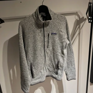 Grå Patagonia fleece  - En grå Patagonia tröja i storlek M. En perfekt tröja nu till vintern som får plats på en hoodie och under en jacka för riktiga kalla dagar. Nypris 1600 ( sällsynt) mitt pris 899kr. Skick 7/10 om det är något ni undrar över så är det bara att fråga 