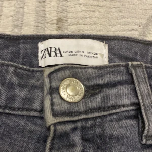 Grå slitna jeans från Zara, strl 36 - Grå jeans från Zara i storlek 36. Modellen är högmidjad och har klassisk femficksdesign. Jeansen har en rak passform och är tillverkade i denim av bomull. Längst ner är dem klippta!