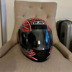 HJC motorcykelhjälm med röd design - Säljer en HJC integralhjälm med coolt röd, svart och silvermönster. Hjälmen har visir och grafiska detaljer i silver och rött över hela skalet. Perfekt för dig som vill sticka ut på vägarna.