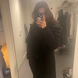 Svart vinterjacka från Everest, strl 38 - Svart lång parkas från Everest med huva och dragkedja framtill.  Perfekt för kalla vintrar och minusgrader. Jackan är fodrad och både vatten- och vindtät. Jackan är i nyskick utan skador eller fläckar.