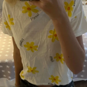 Topp med blommor - Vit topp med kort ärm och löst passform. Tryckta gula blommor med orange mitt över hela. Är i stl 152 men passar mig som har xs-s, köpt på ZARA. Säljer pga att den inte kommer till användning. Den har två små hål, men de syns inte. Hör av er om frågor och tveka inte med prisförslag!❤️
