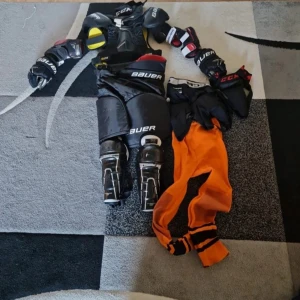 Bauer Supreme S29 hockeyväst svart/gul - Supreme S29 hockeyväst från Bauer i svart och gul med coola detaljer och skyddande axelpartier. Västen har en sportig design med justerbara remmar och slitstarkt syntetmaterial, perfekt för dig som vill ha maxad rörelsefrihet på isen.