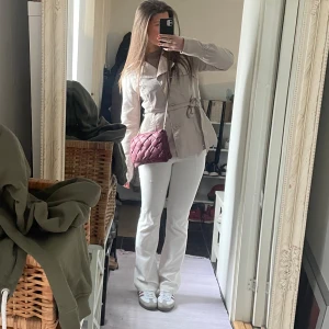 Beige trenchcoat Only - Snygg beige trenchcoat med knytbälte i midjan och klassisk krage. Jackan har knappar framtill och en stilren, figurnära passform som ger en clean look. Perfekt för dig som gillar minimalistisk stil och vill ha en jacka som funkar till många outfits.