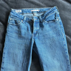 Levi's Low Pitch Straight jeans blå - Säljer ett par klassiska blå Levi's Low Pitch Straight jeans i modell med låg midja och raka ben. Jeansen har fem fickor, bälteshällor och den ikoniska Levi's-lappen bak. Perfekta för dig som gillar en tidlös och avslappnad look.