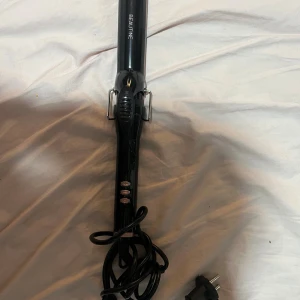 Beautine Locktång - Snygg och stilren locktång från Beautine i svart utförande. Utrustad med tre knappar för enkel temperaturkontroll. Produkten ser ut att vara i gott skick utan synliga defekter eller slitage. Perfekt för att skapa vackra lockar snabbt och smidigt.