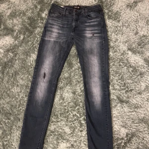 Jack&Jones jeans - Snygga mörkblå skinny jeans från jack&jones med slitningar på låret och lätt tvättad look. Klassisk femficksmodell med dragkedja och knapp. Jeansen har smal passform och är tillverkade i stretchigt denim för extra komfort.
