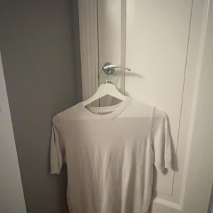 Vit basic t-shirt i bomull - Enkel och stilren vit t-shirt med rund halsringning och korta ärmar. Perfekt att matcha med jeans eller shorts för en clean look. Tillverkad i mjuk bomull som känns skön mot huden.