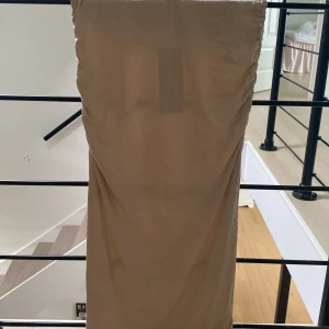 Beige långkjol från Gina Tricot - Säljer en beige långkjol från Gina Tricot i mjukt och stretchigt material. Kjolen är aldrig använd och har fortfarande kvar lapparna från i butiken 