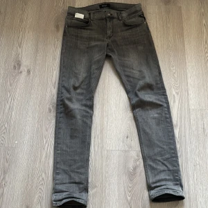 Grå Replay jeans i slim fit - Säljer ett par grå jeans från Replay med klassisk femficksdesign och snygga detaljer på bakfickorna. Jeansen har en slim passform och är tillverkade i mjukt denimtyg som sitter skönt. Perfekta för dig som gillar en stilren och modern look. Kommer med kvittot. 