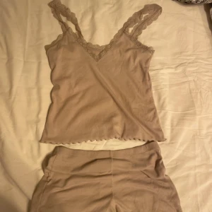 Beige linnetopp med spets från H&M - Supersöt beige linnetopp från H&M med breda spetsband och v-ringning. Toppen är ribbad och har en lätt vågig kant nertill. Tillverkad i mjuk bomullsblandning med polyester. Perfekt för en chill och stilren look.