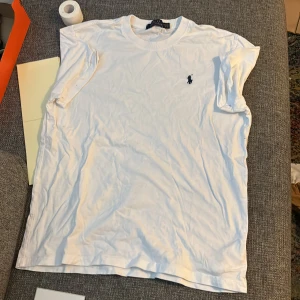 Vit t-shirt från Polo Ralph Lauren - Vit klassisk t-shirt från Polo Ralph Lauren med broderad marinblå logga på bröstet. Rund halsringning och korta ärmar. Tillverkad i mjuk bomull för skön känsla. Perfekt för en clean och stilren look.