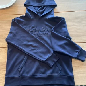 Polo Ralph lauren hoddie - Snygg mörkblå hoodie från Polo Ralph Lauren med broderad logga framtill. Klassisk modell med huva, magficka och långa ärmar. Köpte den nyligen för 1700kr men den va för liten. Perfekt nu när det närmar sig kallare tider🥶