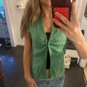 Grön kortärmad skjorta med knappar - Snygg grön skjorta med korta ärmar och knappar framtill. Skjortan har lätt rynkade detaljer vid bröstet och två fickor framtill. Materialet känns lätt och luftigt, perfekt för varmare dagar. Passar dig som gillar en chill och enkel stil.🌸