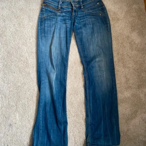 Levi's blå bootcut jeans - Säljer ett par klassiska blå Levi's jeans med bootcut passform. Jeansen har snygga slitningar, kontrastsömmar och fem fickor. Tillverkade i robust denim med den ikoniska röda Levi's-lappen på bakfickan. Perfekta för en avslappnad och trendig look. Har lite slitningar i grenen och en liten färgfläck se bilder. Innerbenslängden är 74cm och midjemåttet är 38cm. Pris går att diskutera 