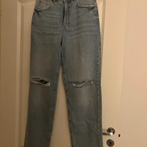 Ljusblå ripped jeans från Na-Kd - Snygga ljusblå jeans från Na-Kd med raka ben och slitna detaljer vid knäna. Hög midja och klassisk femficksmodell. Perfekta för en avslappnad och trendig look.
