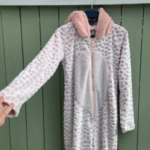 Rosa prickig pyjamas overol från Hunkemöller - Supermysig pyjamas overol (hoodie ) i fleece från Hunkemöller, storlek S. Ljusrosa med prickigt mönster och fluffig huva. Långärmad och hel dragkedja framtill, perfekt för chilliga dagar. Stort ljust parti på magen ger extra cozy känsla. fleecehoodie.Finns liten grön märke på baksidan den går säkert bort på tvätten eller på något sätt därav de låga priset 