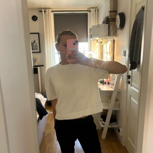 Vit stickad croppad tröja från Gina Tricot - Säljer en vit stickad tröja från Gina Tricot med korta ärmar och croppad passform. Tröjan har rund hals och ribbade detaljer vid halsringning, ärmslut och nederkant. Perfekt för dig som gillar enkel och clean stil.